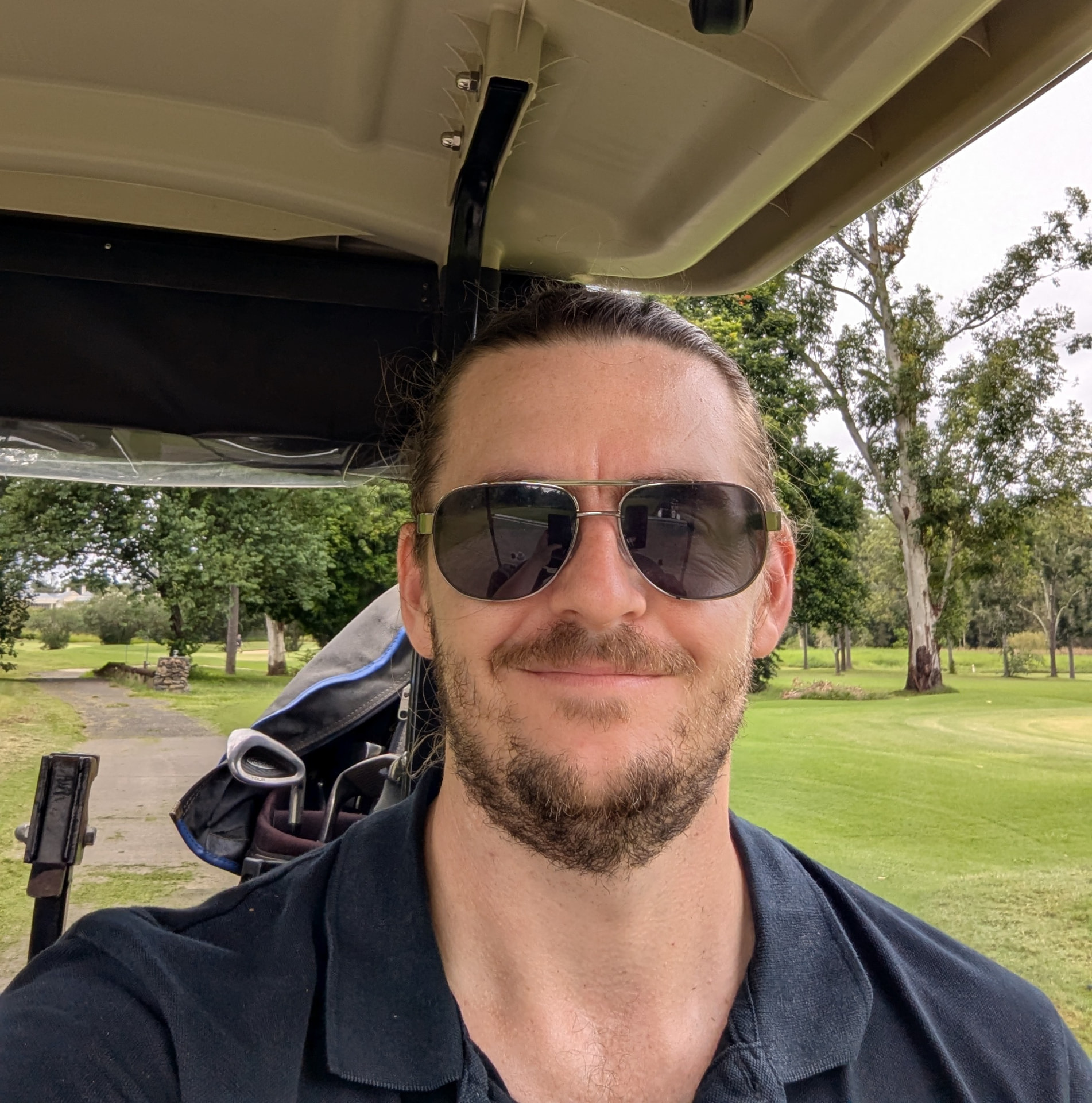 Jarryd Lacey in a golf cart on a tree-lined course